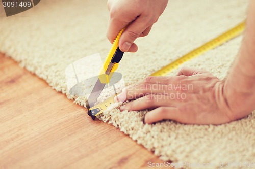 Image of close up of male hands cutting carpet