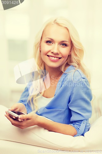 Image of smiling woman with smartphone at home