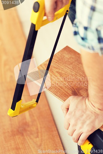 Image of close up of male hands cutting parquet floor board