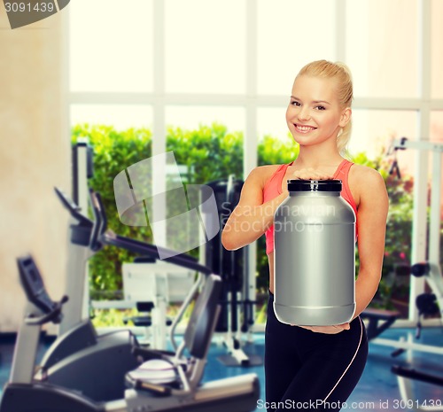 Image of smiling sporty woman with jar of protein