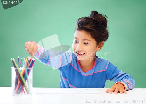 Image of happy school girl drawing with coloring pencils