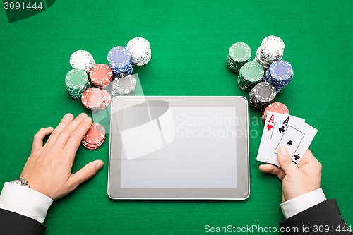 Image of casino poker player with cards, tablet and chips