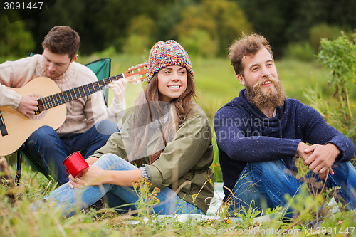 Image of group of smiling friends with guitar outdoors