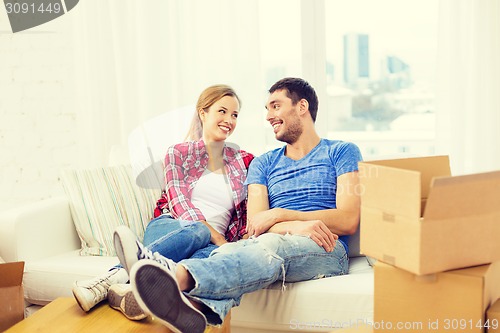 Image of smiling couple relaxing on sofa in new home