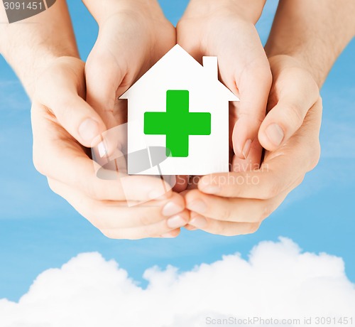 Image of hands holding paper house with green cross