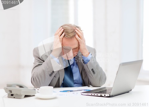 Image of upset older businessman with laptop and telephone