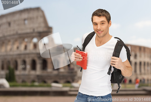 Image of happy young man with backpack and book travelling