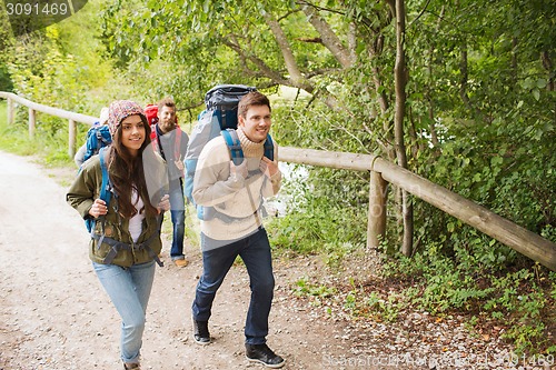 Image of group of smiling friends with backpacks hiking