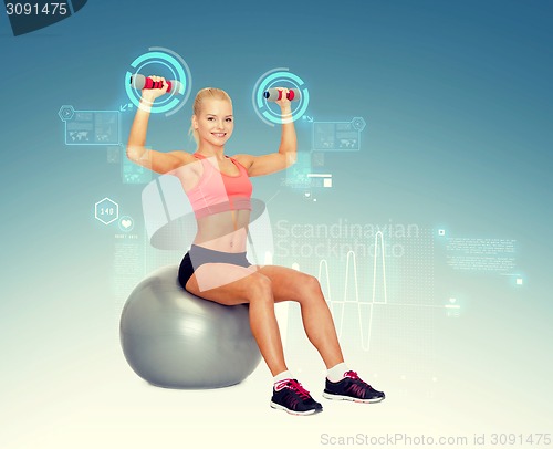 Image of woman with dumbbells sitting on fitness ball