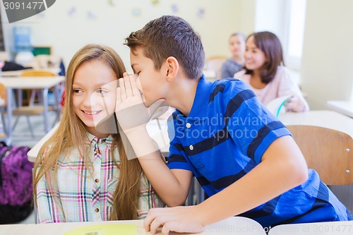 Image of smiling schoolboy whispering to classmate ear