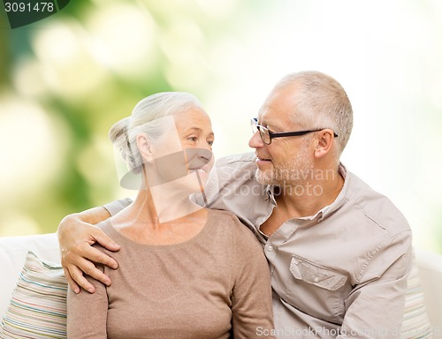 Image of happy senior couple hugging on sofa at home