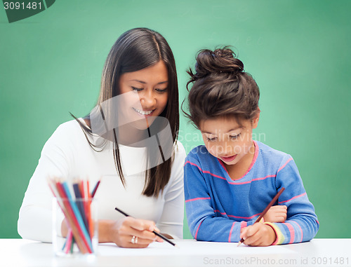 Image of happy teacher and little school girl drawing