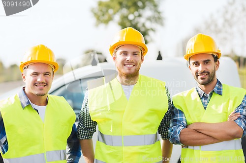 Image of group of smiling builders in hardhats outdoors