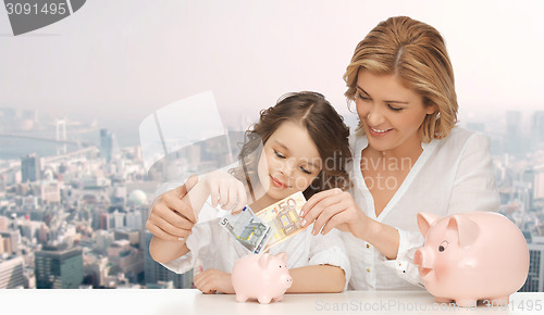 Image of mother and daughter putting money to piggy banks