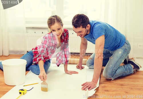 Image of smiling couple smearing wallpaper with glue