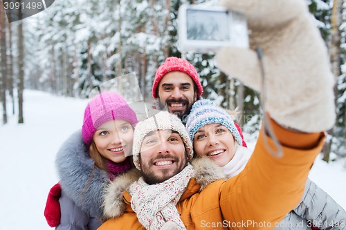 Image of smiling friends with camera in winter forest