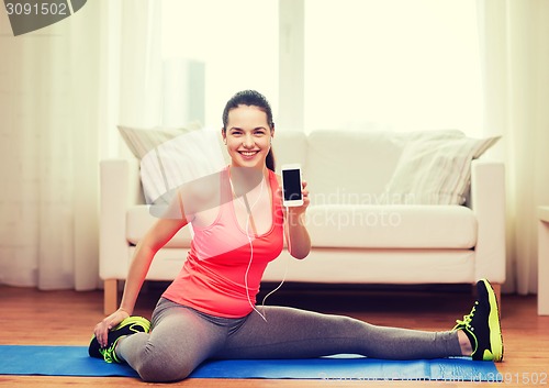 Image of smiling teenage girl streching on floor at home