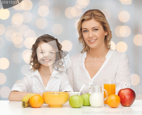 Image of happy mother and daughter eating breakfast