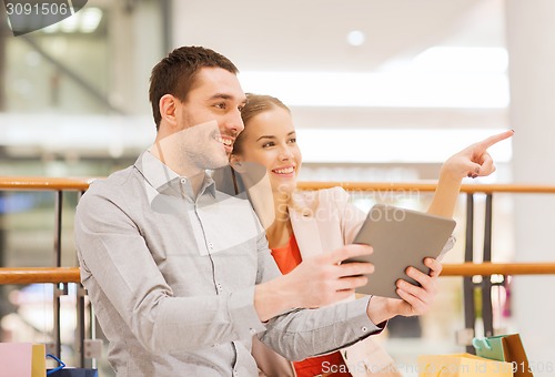 Image of couple with tablet pc and shopping bags in mall