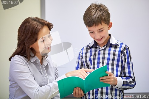 Image of school boy with notebook and teacher in classroom