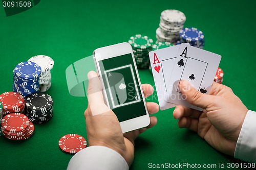 Image of casino player with cards, smartphone and chips