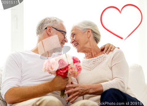 Image of happy senior couple with bunch of flowers at home