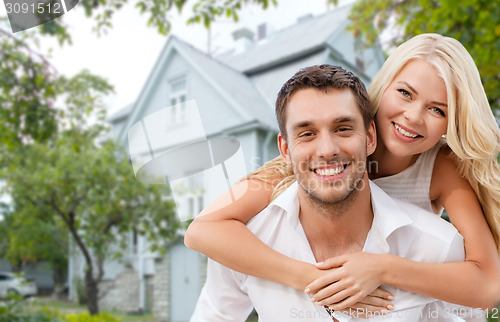 Image of smiling couple hugging over house background