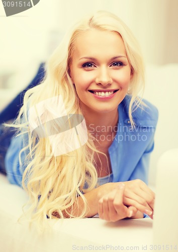 Image of smiling young woman lying on sofa at home