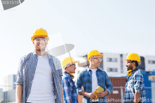 Image of group of smiling builders in hardhats outdoors