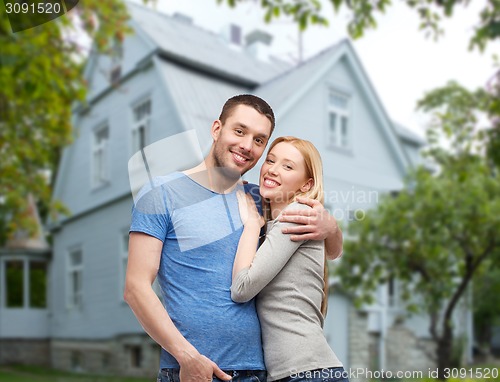 Image of smiling couple hugging over house background