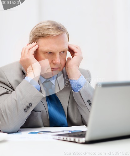 Image of upset older businessman with laptop in office