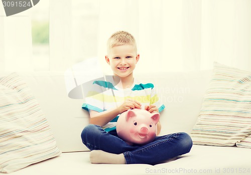 Image of smiling little boy with piggy bank and money