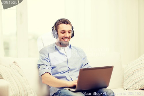 Image of smiling man with laptop and headphones at home
