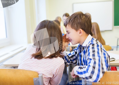 Image of smiling schoolgirl whispering to classmate ear