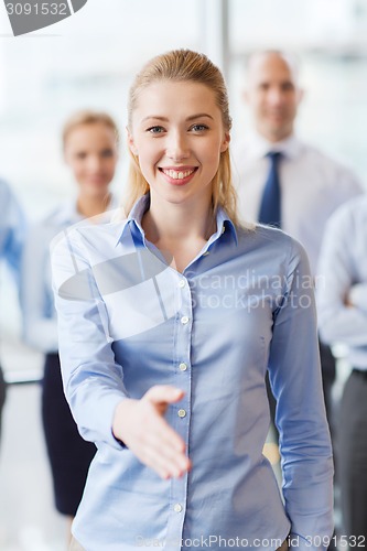 Image of smiling businesswoman making handshake in office