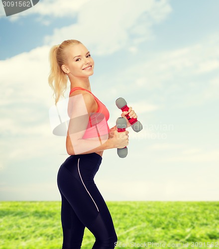 Image of smiling beautiful sporty woman with dumbbells