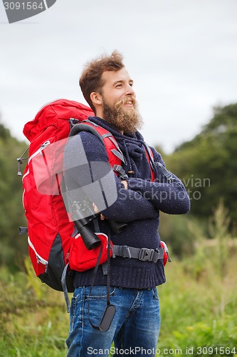 Image of smiling man with backpack and binocular outdoors