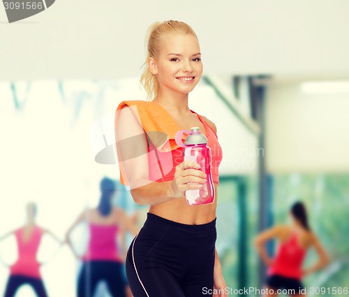 Image of smiling sporty woman with water bottle and towel