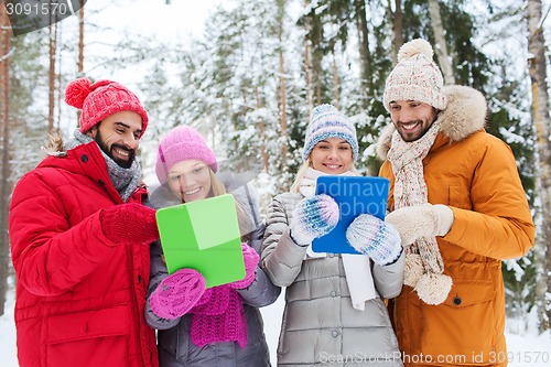 Image of smiling friends with tablet pc in winter forest
