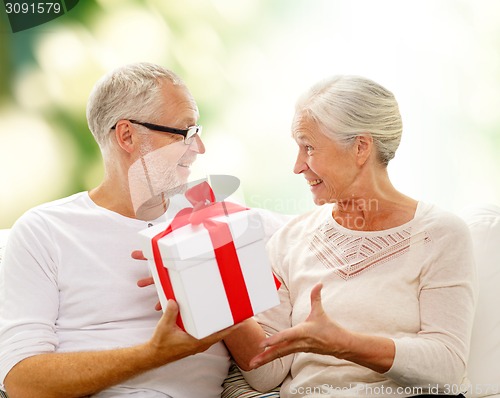 Image of happy senior couple with gift box at home