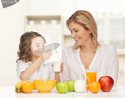 Image of happy mother and daughter eating breakfast