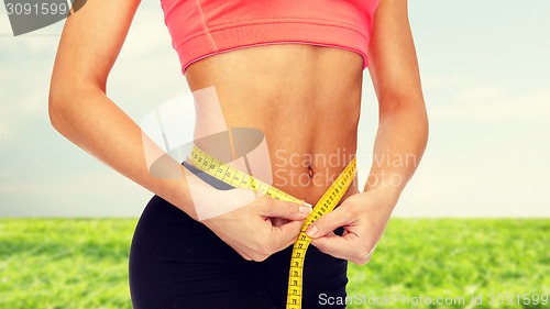 Image of close up of female hands measuring waist