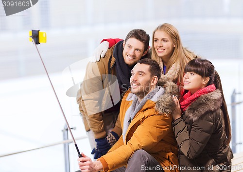 Image of happy friends with smartphone on skating rink