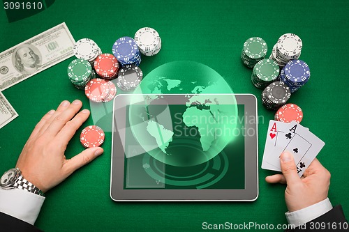 Image of casino poker player with cards, tablet and chips