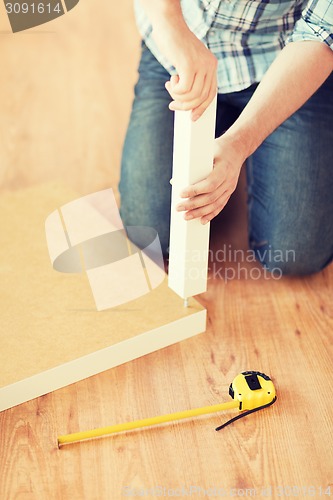 Image of close up of male hands assemblying legs to table