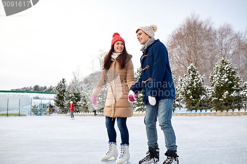 Image of happy couple ice skating on rink outdoors