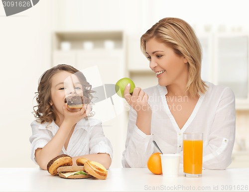 Image of happy mother and daughter eating breakfast