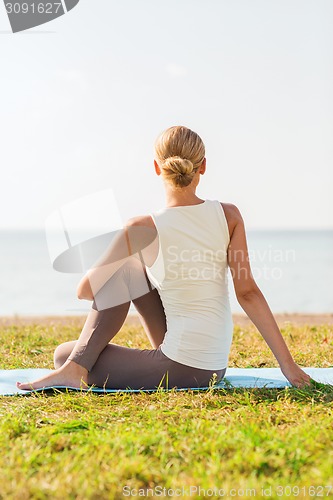 Image of woman making yoga exercises outdoors