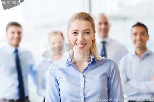 Image of smiling businesswoman with colleagues in office