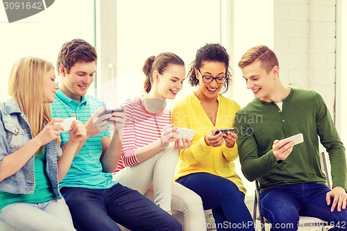 Image of smiling students with smartphone texting at school